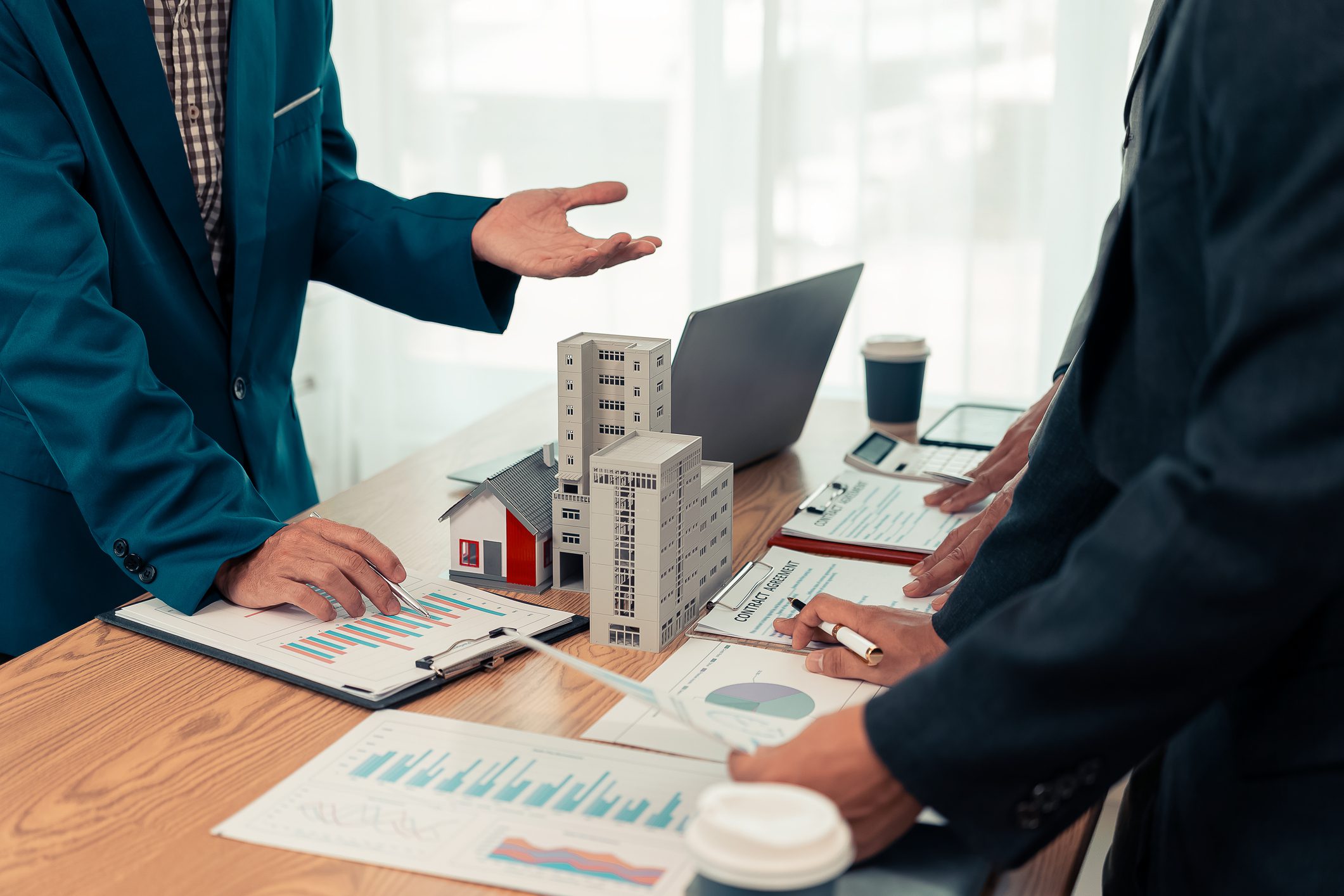Business meeting with architectural models on table.