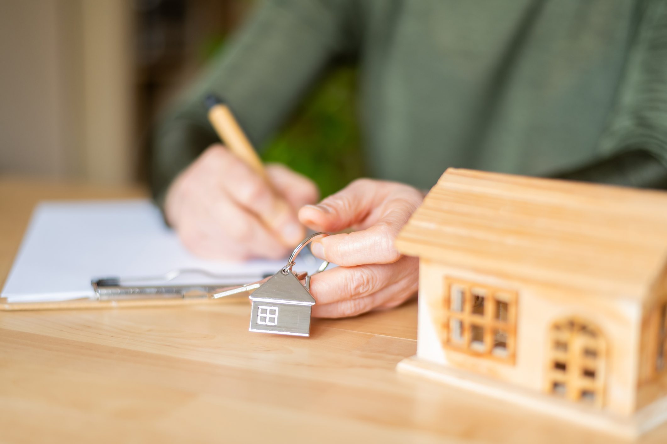 Person holding house key, signing documents.
